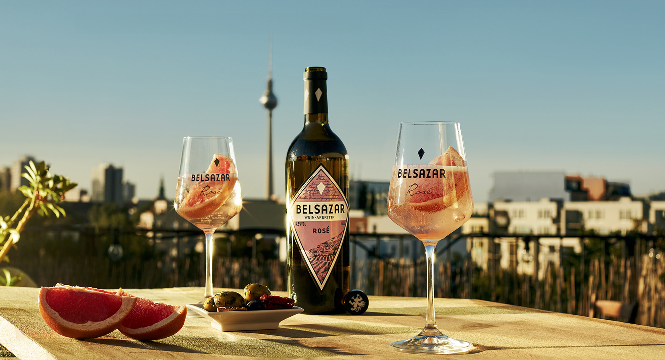Bottle and glass of Belsazar on a table overlooking a panoramic view of Berlin.